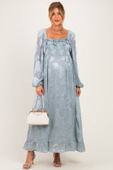 woman wearing a light blue floral maternity maxi dress with long sleeves and a baby bump, holding a handbag