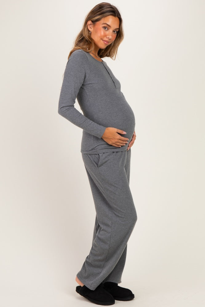 woman wearing a gray long sleeve maternity top and matching pants, cradling her baby bump
