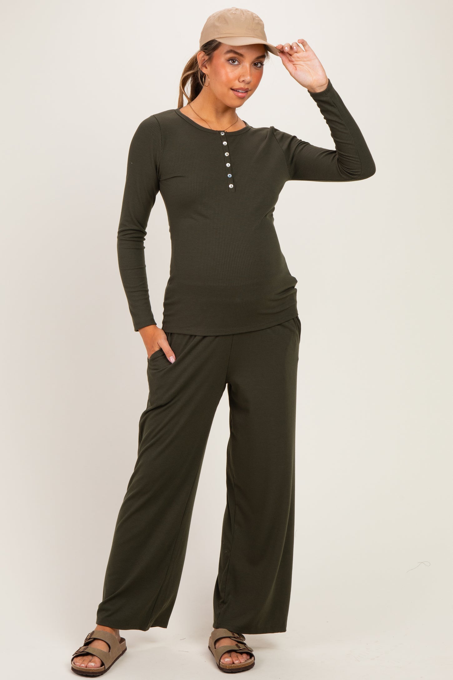 woman wearing an olive green maternity loungewear set with long sleeves and wide-leg pants, showcasing a baby bump