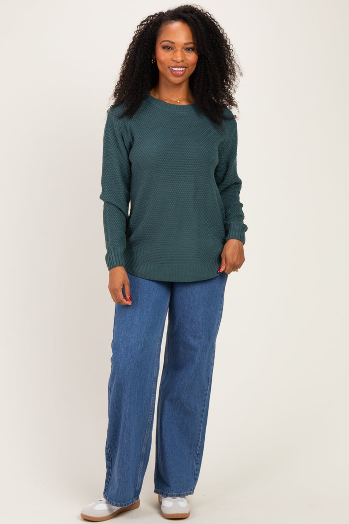 woman wearing a dark green textured long sleeve sweater and wide leg denim jeans