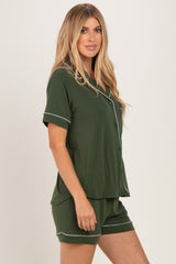 woman wearing a dark green short sleeve pajama set with white piping details