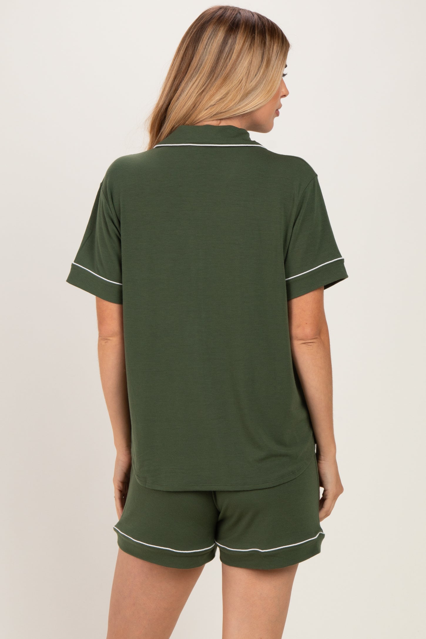 woman wearing a green short sleeve top with white trim and matching shorts, viewed from the back