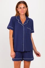 woman wearing a navy blue short sleeve pajama set with white piping details and a front pocket