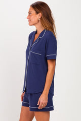 woman wearing a navy blue short sleeve pajama set with white piping and a chest pocket
