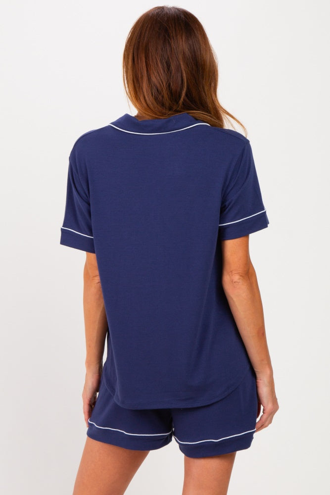 woman wearing a navy blue short sleeve pajama set with white piping, showing the back view