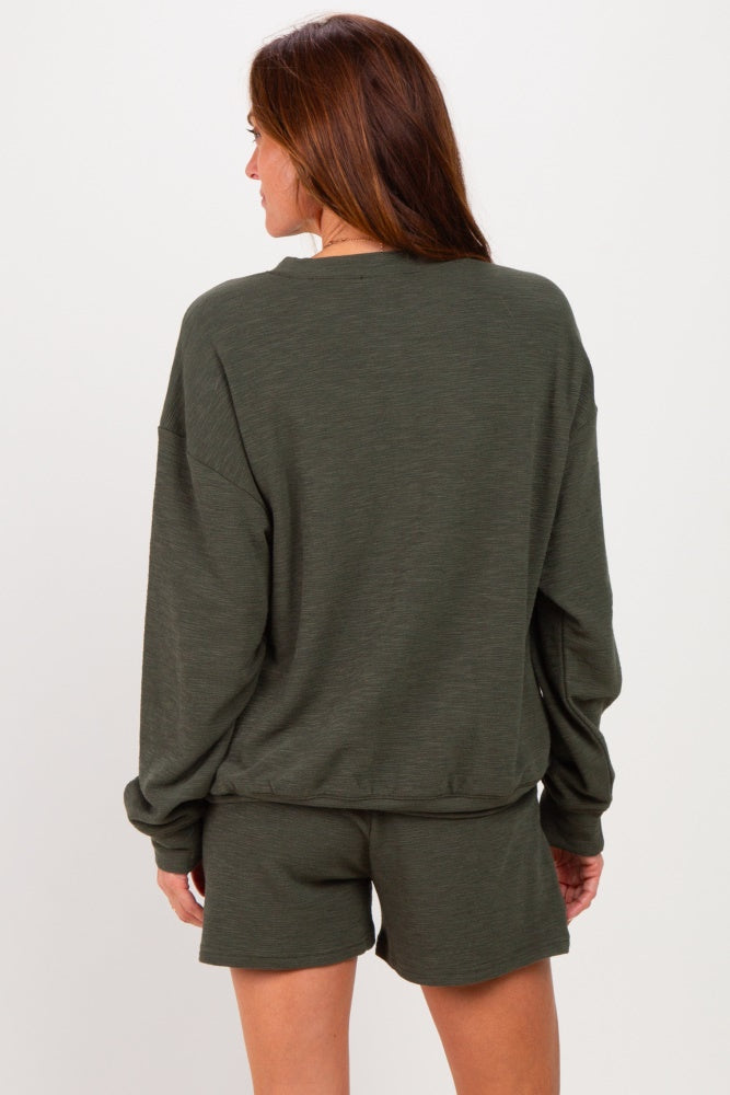 woman wearing a dark green oversized sweatshirt and matching shorts, viewed from the back