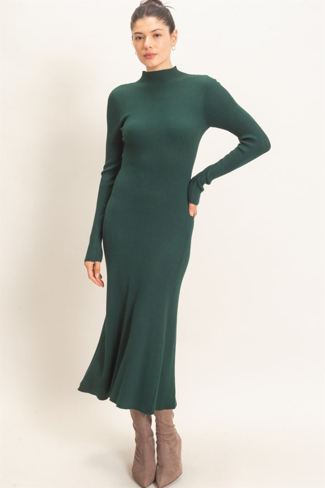 woman wearing a fitted green ribbed midi dress with long sleeves and a high neckline, styled with taupe ankle boots