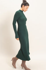 woman wearing a ribbed dark green long sleeve midi dress paired with beige high-heeled boots.