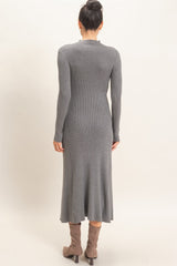 woman wearing a fitted gray ribbed long sleeve dress that falls below the knee with a flared hem and paired with knee-high boots