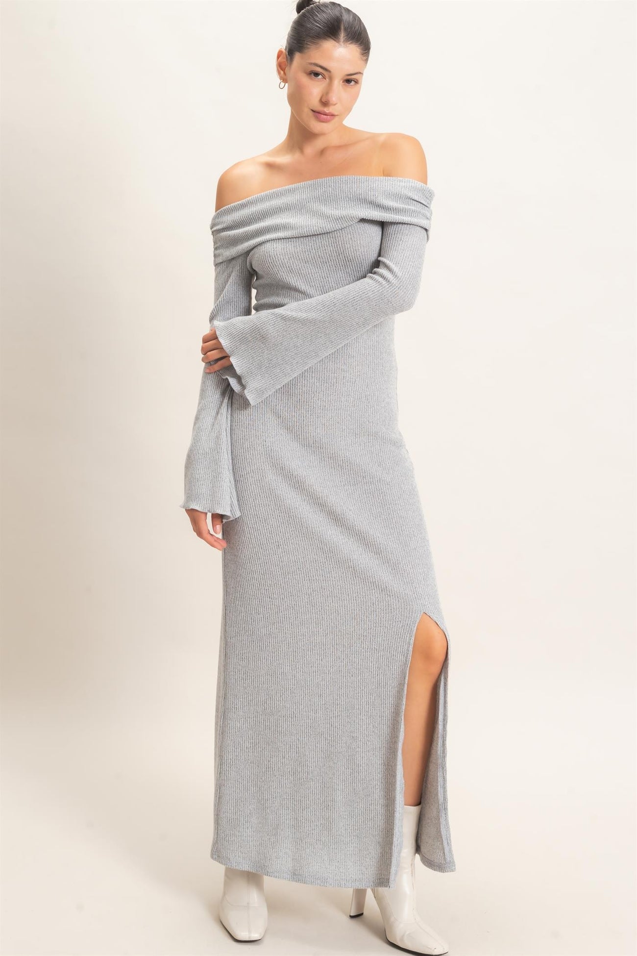 woman wearing a light gray off-the-shoulder ribbed maxi dress with long sleeves and a side slit