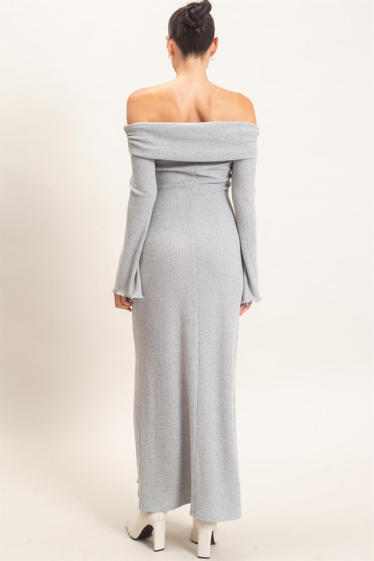 woman wearing a grey off-the-shoulder long sleeve maxi dress with a ribbed texture, showing the back view