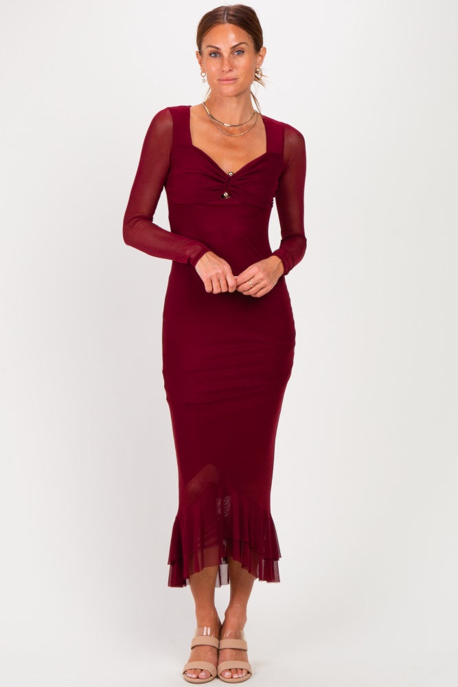 woman wearing a burgundy long sleeve fitted midi dress with ruffle hem and a front twist detail
