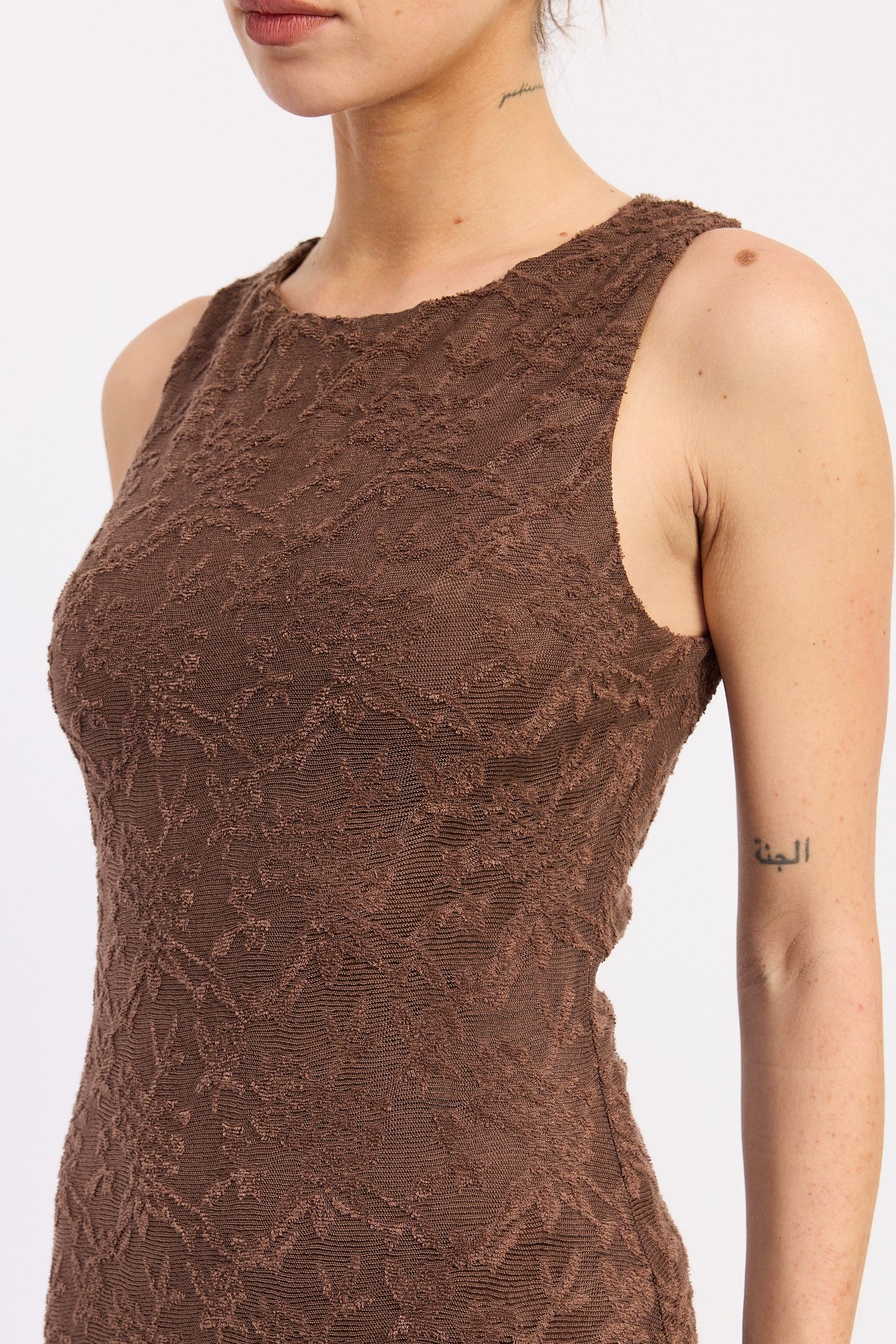 woman wearing a brown sleeveless dress with textured floral detailing