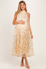 woman wearing a flowy beige maternity dress with floral embroidery, gently cradling her baby bump
