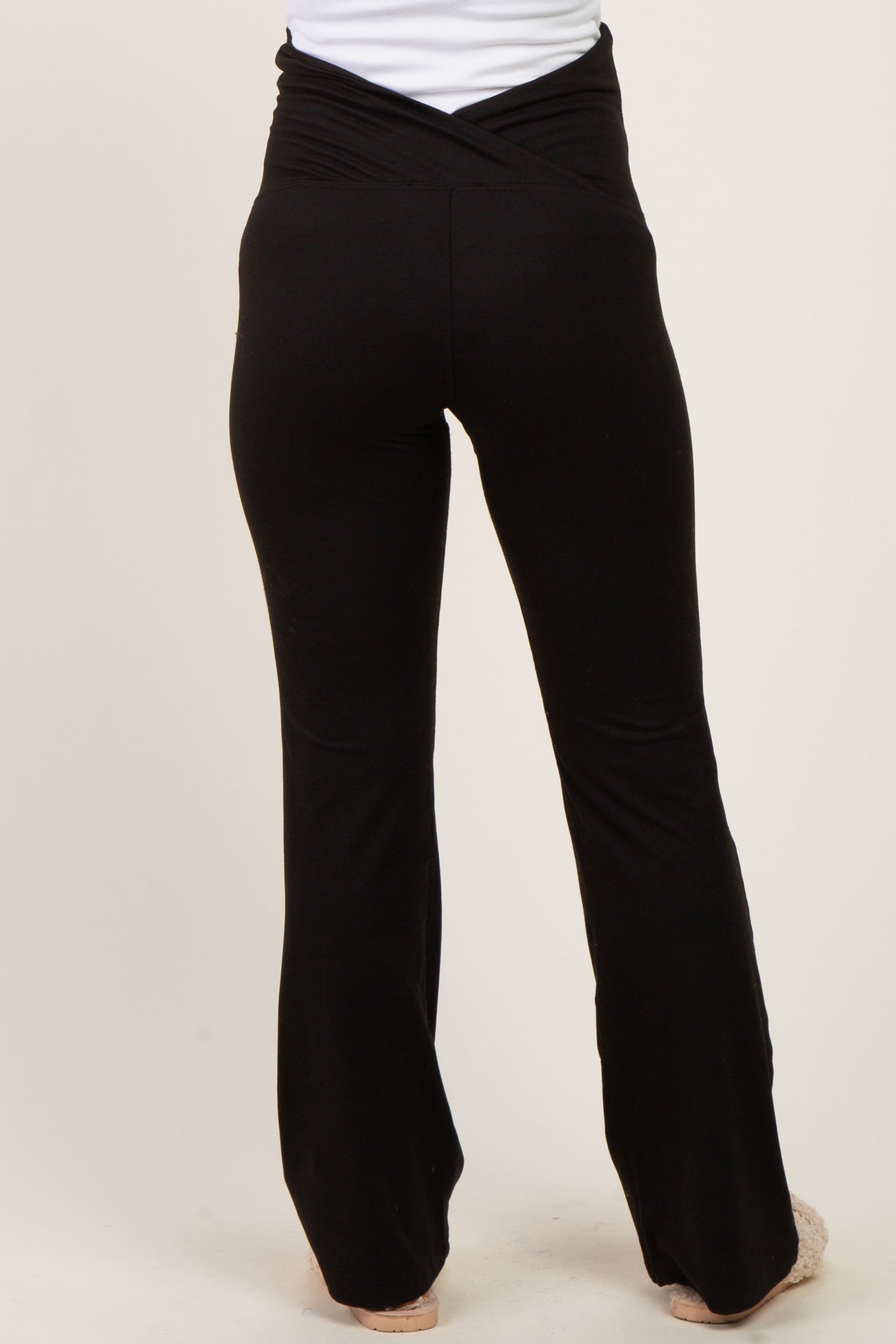 woman wearing black maternity yoga pants with a crossover waistband, view from the back