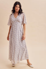 woman wearing a light purple floral maxi dress with short flutter sleeves and a flowy silhouette