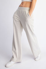 woman wearing light beige wide-leg lounge pants with pockets and an elastic waistband