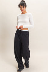 woman wearing a white long sleeve top and black wide-leg sweatpants with pockets