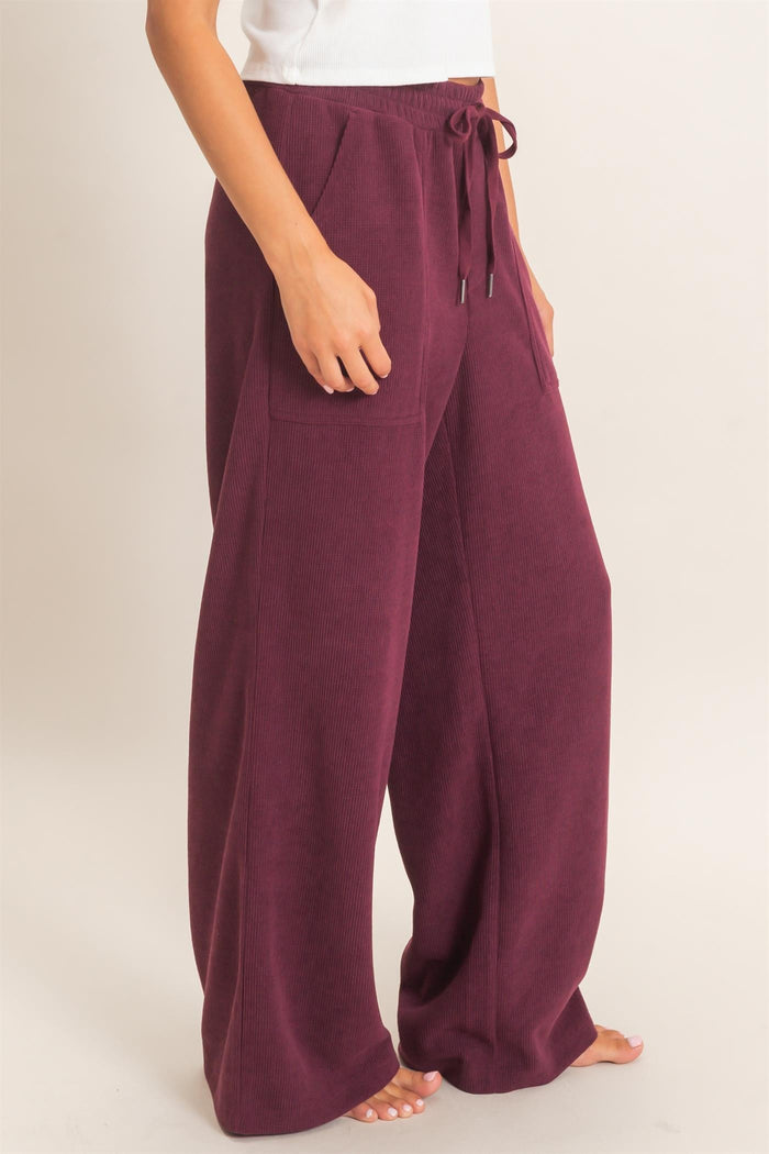woman wearing burgundy wide-leg lounge pants with a drawstring waist and side pockets