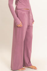 woman wearing loose-fitting mauve lounge pants with an elastic waistband and side pockets