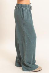 woman wearing teal wide-leg lounge pants with pockets and an elastic waistband
