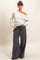 woman wearing a light gray off-shoulder sweater with floral print and black wide-leg sweatpants
