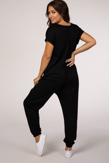 woman wearing a black short sleeve jumpsuit, styled for maternity wear, with a relaxed fit and back button detail