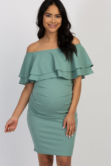 woman wearing a mint green off-shoulder ruffled maternity dress with a visible baby bump
