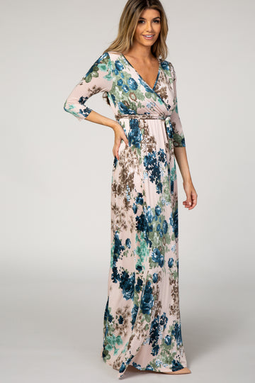woman wearing a floral maxi dress with a wrap style and 3/4 sleeves in shades of blue and green
