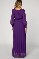 woman wearing a purple long sleeve maternity dress with a flowing skirt and sheer sleeves, showing the back view