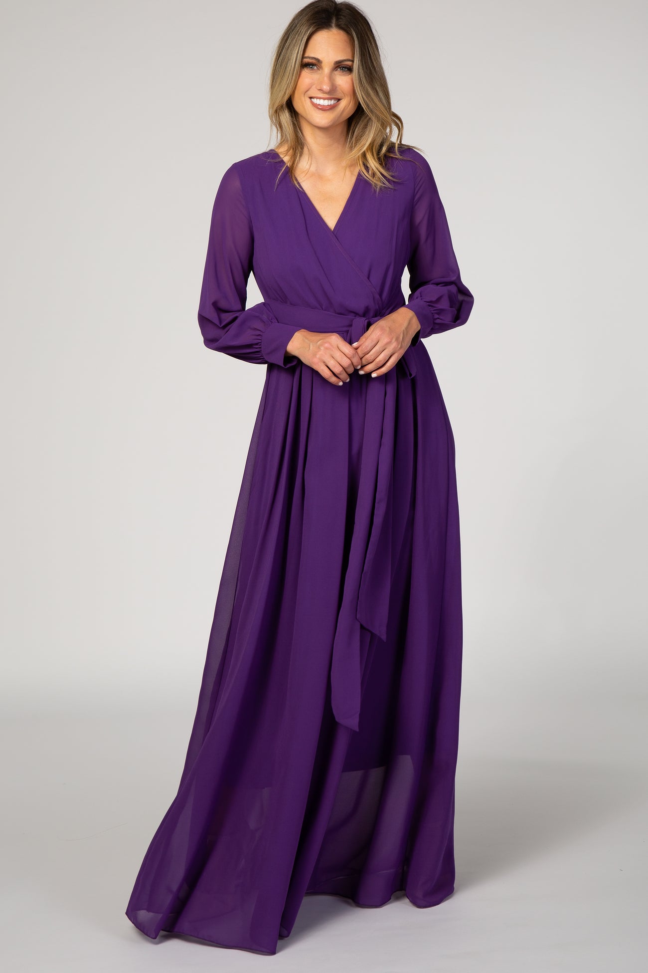 woman wearing a purple long sleeve wrap maxi dress with a tie waist and a flowy skirt