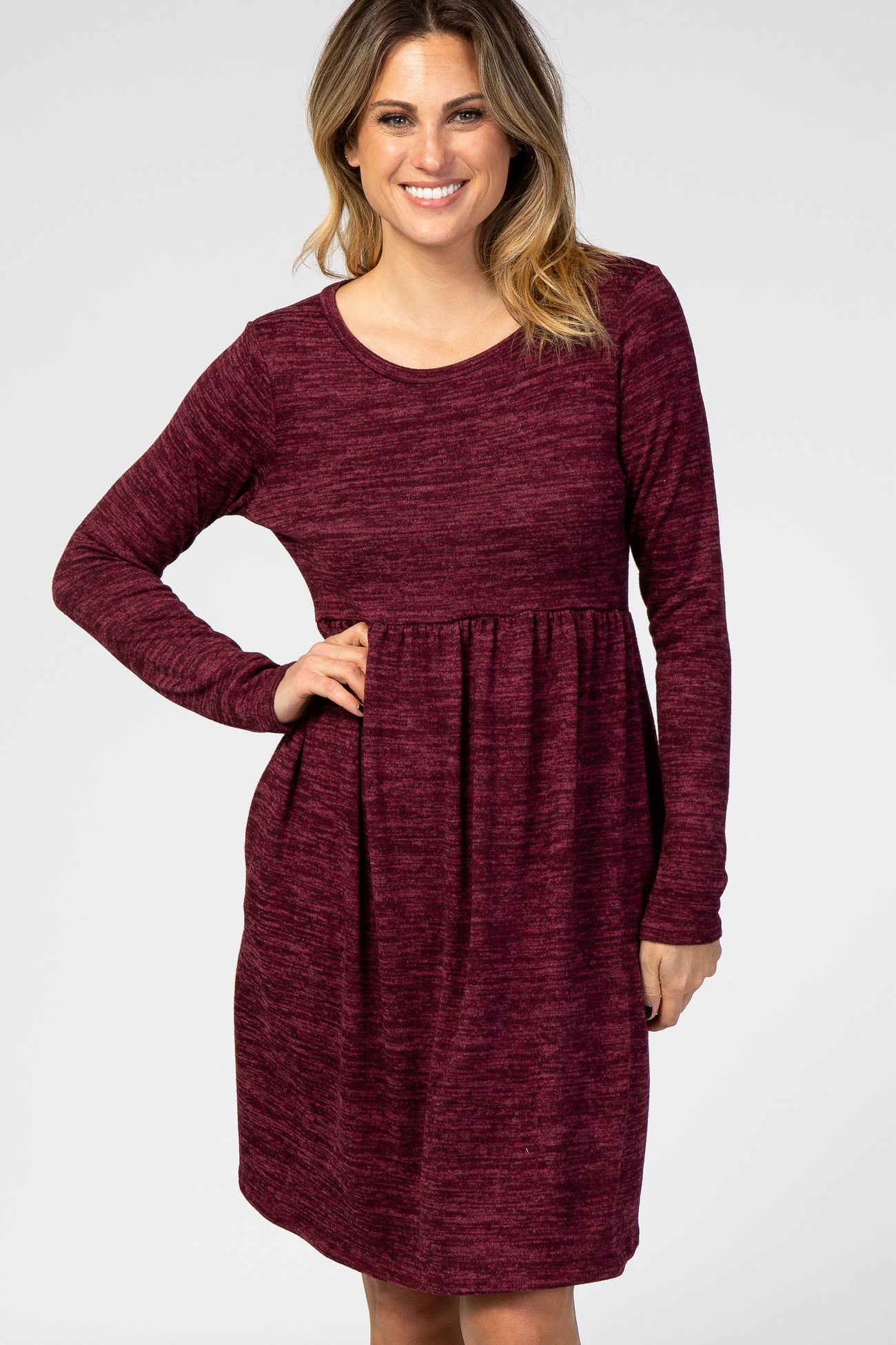 woman wearing a burgundy long sleeve dress with a fitted bodice and a flared skirt
