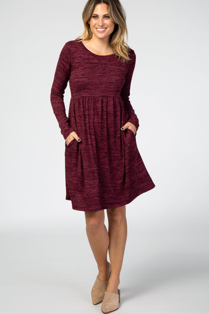 woman wearing a burgundy long sleeve dress with side pockets and a relaxed fit