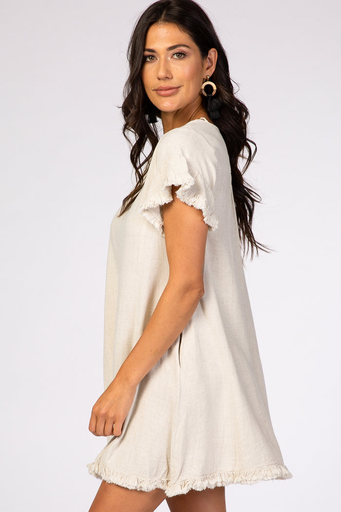 woman wearing a beige short sleeve dress with ruffled sleeves and hemline details