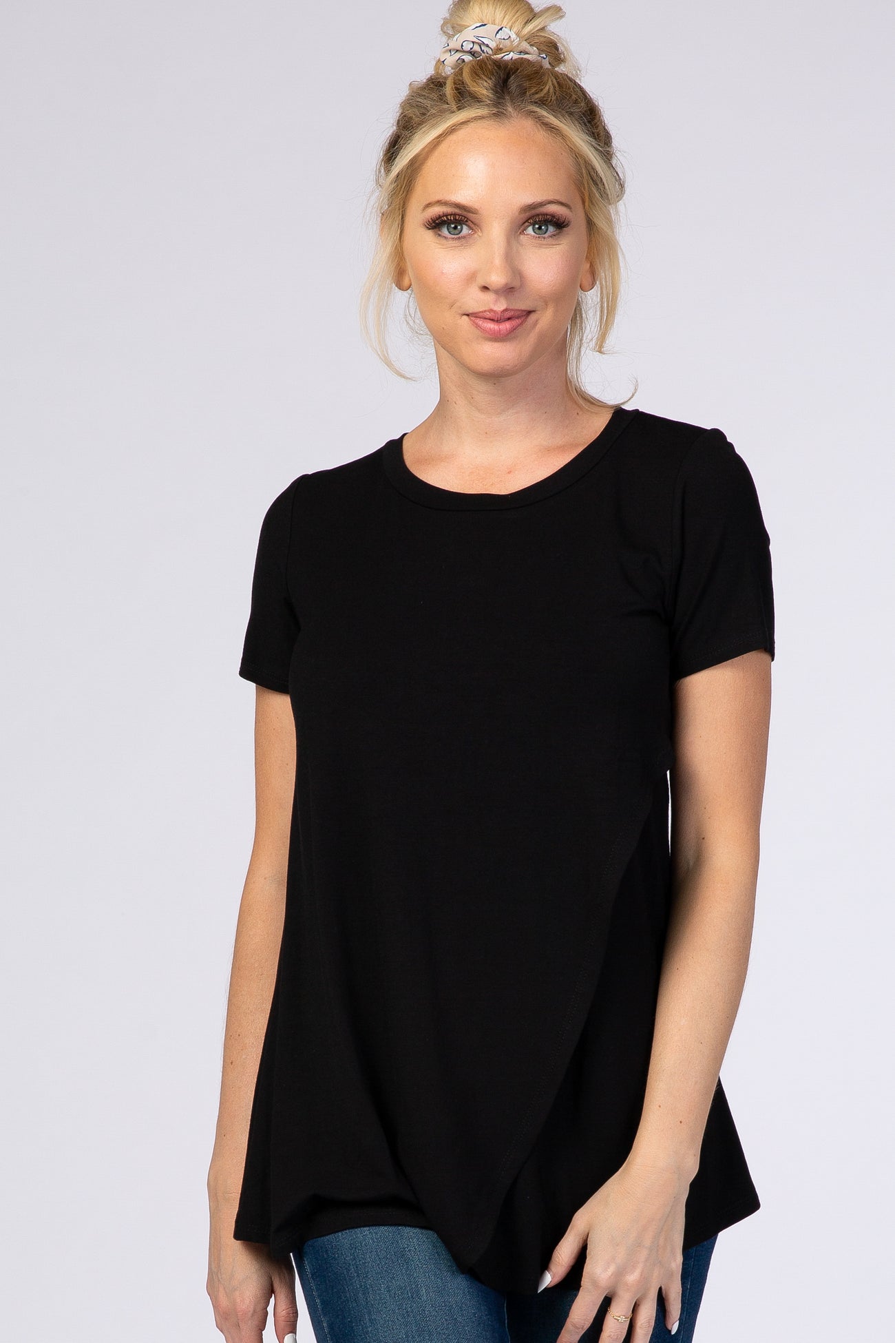woman wearing a black short sleeve top with a flowy hem and paired with blue jeans