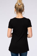 woman wearing a black short sleeve top from the back, styled with jeans and hair in a bun