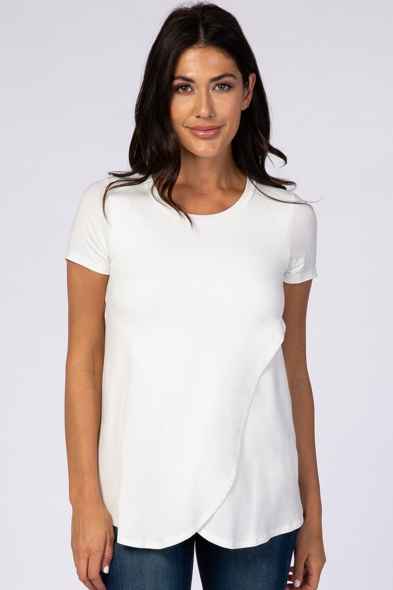 woman wearing a white short sleeve top with an asymmetrical hem and round neckline, styled with blue jeans