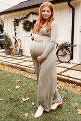 woman wearing a sage green off-shoulder maternity dress and holding her baby bump