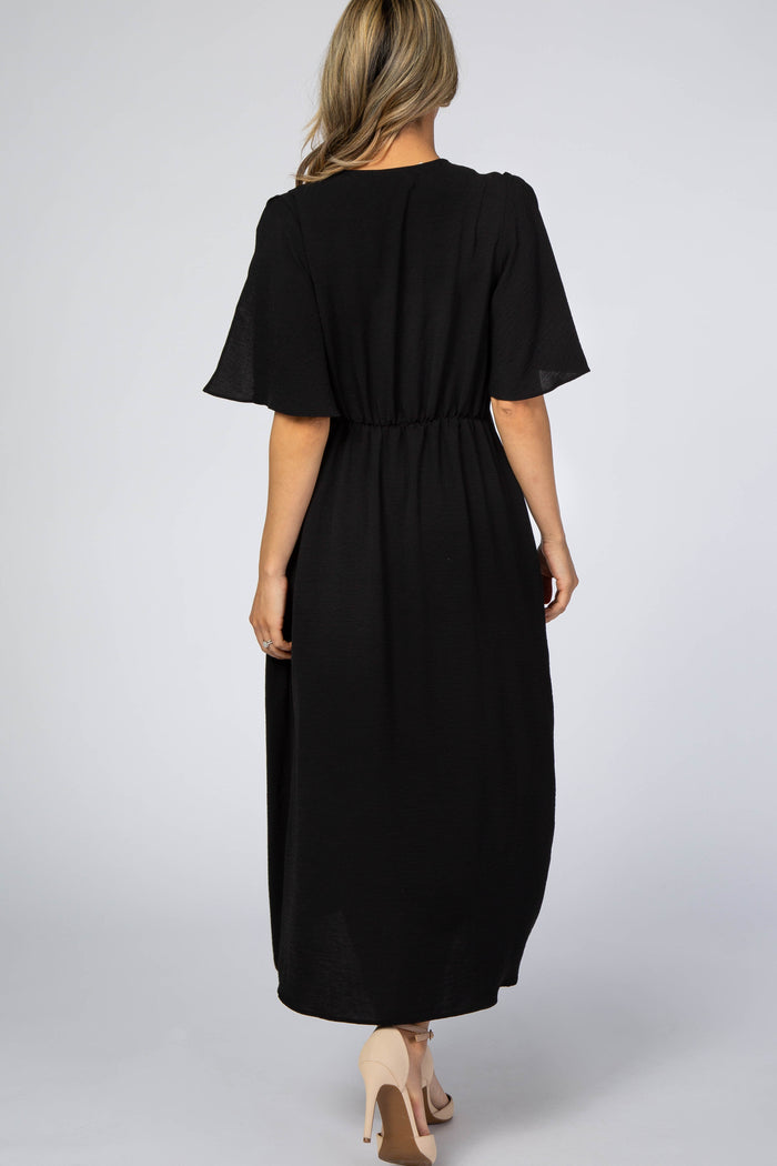 woman wearing a black maxi dress with short flutter sleeves and elastic waist, shown from the back