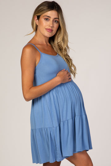 woman wearing a light blue maternity dress with a tiered skirt, showing her baby bump