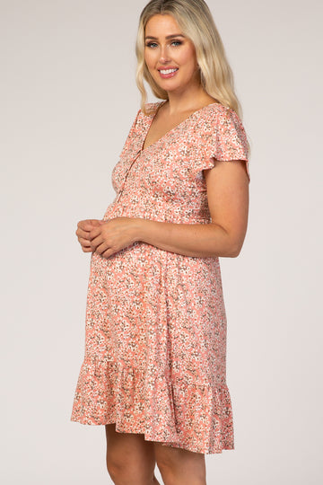 woman wearing a pink floral maternity dress with short sleeves and a ruffled hem, showing her baby bump