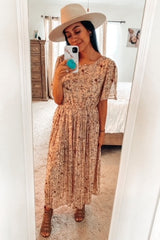 woman wearing a floral midi dress with short sleeves and a pleated skirt, paired with a wide-brimmed hat and strappy sandals