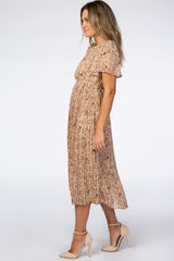 woman wearing a beige floral pleated midi dress with short sleeves and heeled shoes
