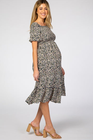woman wearing a black floral maternity dress with a ruffled hem and a visible baby bump