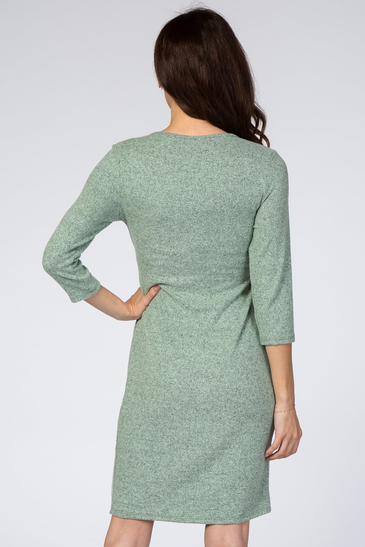 woman wearing a light green three-quarter sleeve dress, seen from the back