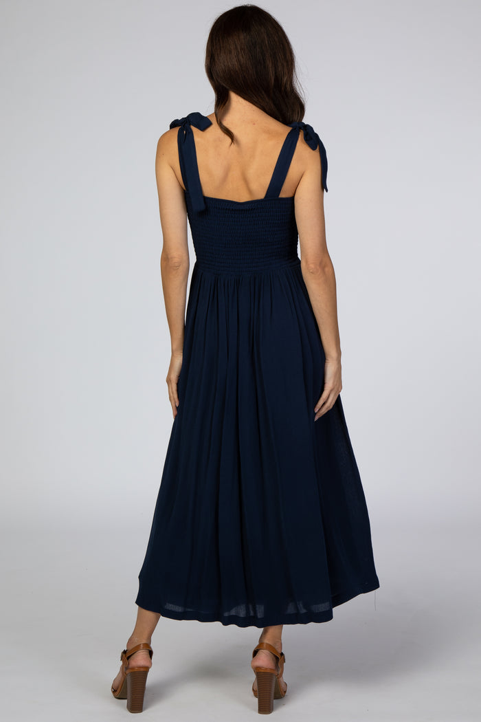 woman wearing a navy blue maxi dress with tie straps and a smocked bodice, shown from the back