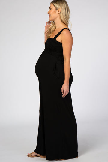 woman wearing a black sleeveless maternity jumpsuit, showcasing her baby bump from the side