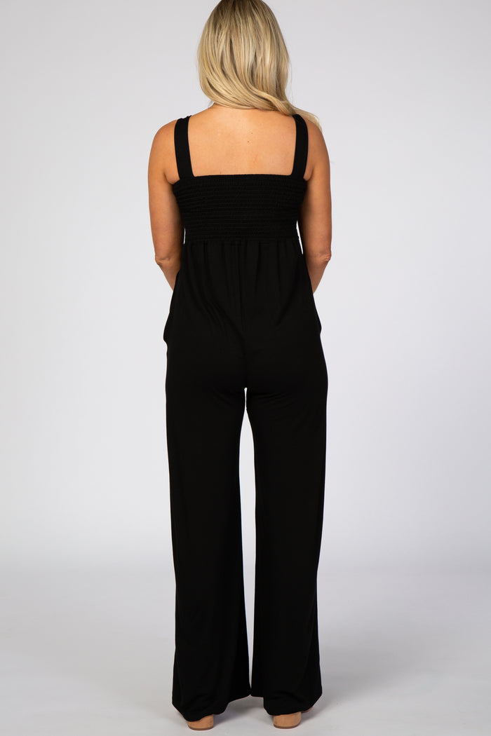 woman wearing a black maternity jumpsuit with a smocked bodice and wide leg pants, shown from the back