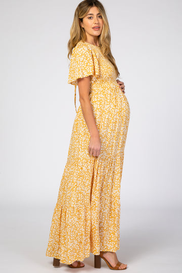 woman wearing a yellow floral maternity maxi dress with short sleeves and a visible baby bump