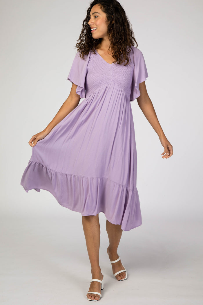 woman wearing a light purple short sleeve dress with a ruffled hem and a smocked bodice